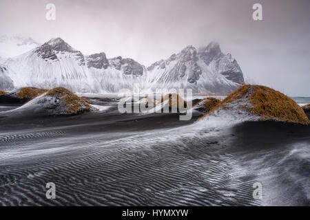 Schwarze Lavastrand mit frischem Schnee, Mount Vestrahorn, Stokknes, Ost-Region, Island Stockfoto