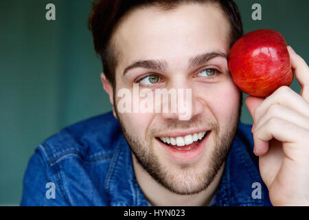 Nahaufnahme Portrait eine attraktive junge Mann hält roten Apfel und denken Stockfoto