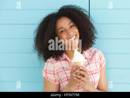 Porträt einer schönen jungen schwarzen Frau lächelnd mit Eis auf blauem Hintergrund hautnah Stockfoto