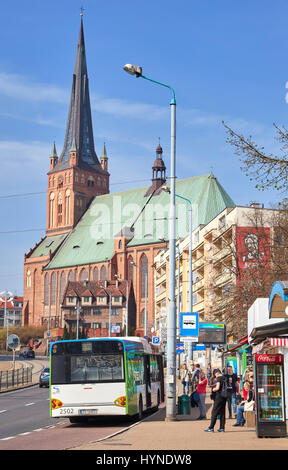 Stettin, Polen - 1. April 2017: Linienbus-Haltestelle mit wartenden Menschen bei Wyszynskiego Street, Cathedral Basilica of St. James der Apostel im Hintergrund. Stockfoto