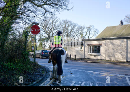 Pferd und Reiter in einem englischen Dorf warten an einer Straßenkreuzung Stockfoto