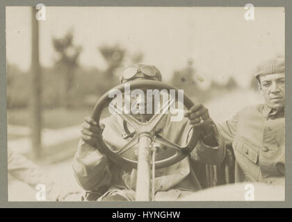 Boxer Jack Johnson (1878-1946) auf der Suche durch das Lenkrad seines Automobils Thomas Flyer mit einem anderen Mann neben ihm sitzen. 6. September 1916. Stockfoto