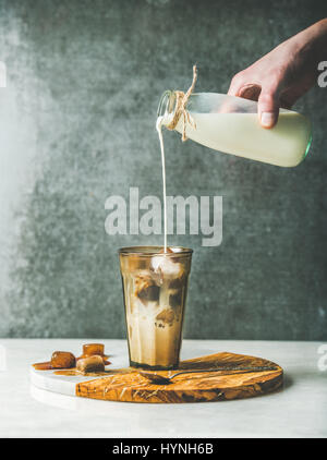 Mannes hand Gießen Milch Iced Latte Caramel Kaffee cocktail Stockfoto