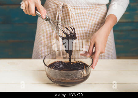 Haus Frau trägt Schürze machen. Schritte der Herstellung Kochen Schokolade Kuchen. Teig mischen Zutaten vorbereiten Stockfoto