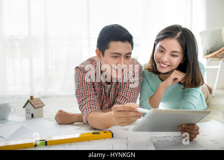 Attraktive junge asiatische erwachsenes paar Hauspläne zu betrachten. Stockfoto