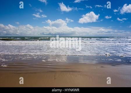 Bournemouth Beach zeigt Rand des Meeres mit der Flut kommen den Sand, ein Spiegelbild der Wolken und blauer Himmel auf dem nassen sandigen Ufer verlassen. Stockfoto