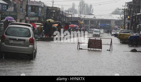 Srinagar, Kaschmir. 6. April 2017.  Fahrzeuge navigieren Sie ihren Weg durch ein Wasser angemeldet-Straße als Fußgänger im Straßenverkehr Teiler gehen. Behörden bekannt, dass alle Schulen und Hochschulen in Kaschmir bis Montag angesichts des schlechten Wetters geschlossen würde. Bildnachweis: Sofi Suhail/Alamy Live-Nachrichten Stockfoto