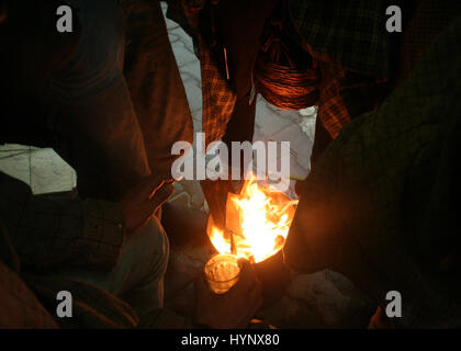 Srinagar, Kaschmir. 6. April 2017. Kashmiri Menschen versuchen, sich in der Nähe von einem kleinen Lagerfeuer wärmen, da die Temperaturen sinken. Behörden bekannt, dass alle Schulen und Hochschulen in Kaschmir bis Montag angesichts des schlechten Wetters geschlossen würde. Bildnachweis: Sofi Suhail/Alamy Live-Nachrichten Stockfoto