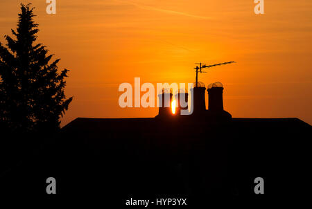 Wimbledon, London, UK. 6. April 2017. Brilliant orange Sonnenuntergang zwischen Schornsteine auf dem Dach in SW London nach einem schönen Frühlingstag in der Hauptstadt. Bildnachweis: Malcolm Park Leitartikel/Alamy Live-Nachrichten. Stockfoto