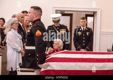 Arlington, Virginia, USA. 6. April 2017. Annie Glenn ist getröstet, als die Fahne drapiert Sarg ihres Mannes erfolgt nach der Trauerfeier in der alten Post-Kapelle, ft. Meyer 6. April 2017 in Arlington, Virginia. Glenn, der erste amerikanische Astronaut, die Erde zu umkreisen und später ein Senator der Vereinigten Staaten, starb im Alter von 95 Jahren am 8. Dezember 2016. Bildnachweis: Planetpix/Alamy Live-Nachrichten Stockfoto