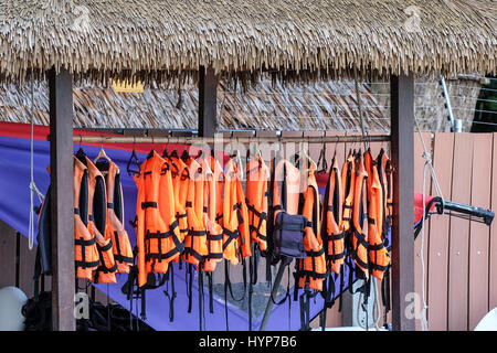 Farbe Orange Schwimmwesten, bedeckt hängt an der Wand der Boot station Stockfoto