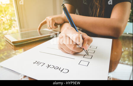 Close-up Hand mit Stift auf Check Liste Papier mit Tablette in Stockfoto