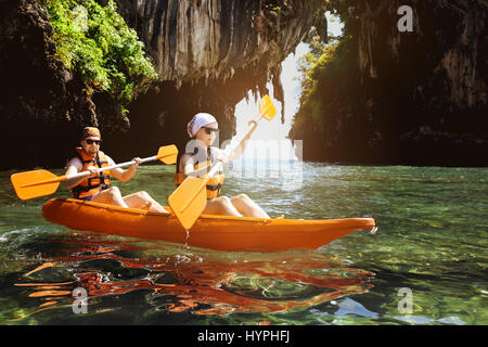 Paar Kajakfahrer schwimmt unter dem Felsen im Meer Stockfoto