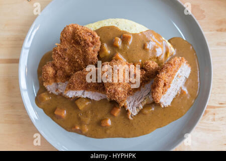 Omelett mit Japanischen Reis Curry und panierte Frittierte Schweinekotelett auf modernen Holz Tisch Stockfoto