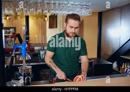 Der Barmann bereitet frischen Saft am Bar. Barista geschnitten Zitrusfrüchten auf t Stockfoto