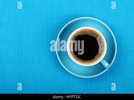 Volle Tasse schwarzen Americano oder instant-Kaffee auf Untertasse über blaue Tischdecke, Nahaufnahme, erhöhten Draufsicht Stockfoto