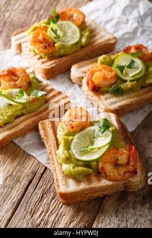 Leckeren Toast mit Guacamole, Garnelen und Kalk Nahaufnahme auf dem Tisch. vertikale Stockfoto