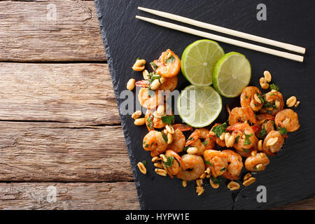 Asiatische Küche: sautierten Garnelen mit Erdnüssen, Kalk und grünen Closeup auf dem Tisch. Horizontale Ansicht von oben Stockfoto