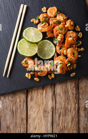 Asiatische Küche: sautierten Garnelen mit Erdnüssen, Kalk und grünen Closeup auf dem Tisch. Vertikale Ansicht von oben Stockfoto