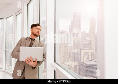 Ernst Businesssman stützte sich auf das Office-Fenster Stockfoto