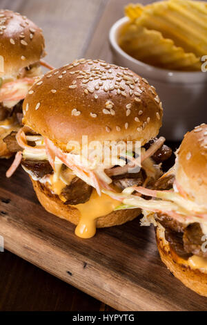 Hausgemachte Mini-Rindfleisch-Burger mit Krautsalat Salat auf kleinen Holzbrett. Grill-Fleisch-Sandwiches auf rustikalen Tisch. Stockfoto