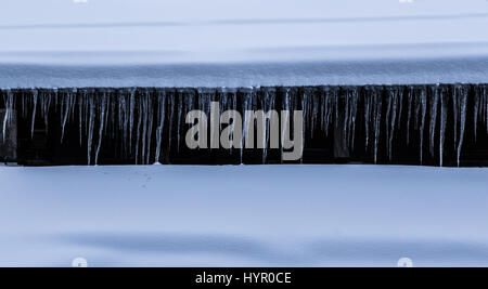 Eiszapfen gebildet hängen von Gosse Schnee bedeckt Alphütte Stockfoto