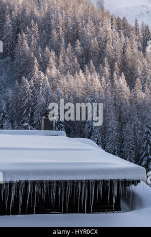 Eiszapfen gebildet hängen von Gosse Schnee bedeckt Alphütte Stockfoto