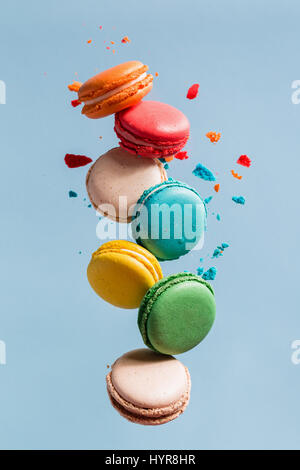 Verschiedene Arten von Makronen in Bewegung fallen auf Licht blauer Hintergrund. Süße und bunte französische Macarons fallen oder fliegen in Bewegung. Stockfoto