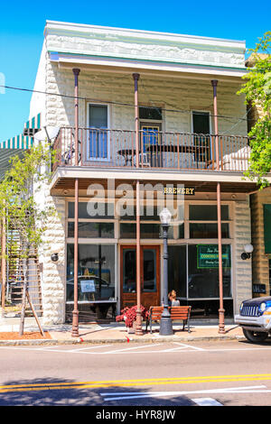 Frau sitzt vor einem Brauhaus Gebäude im Zentrum von Tarpon Springs, Florida Stockfoto