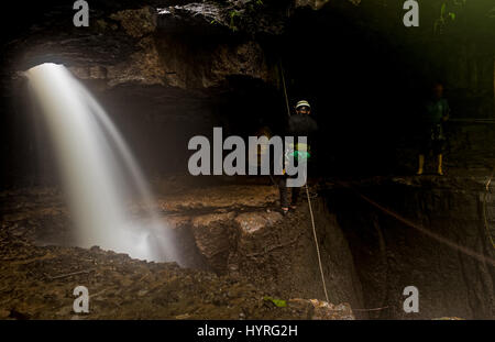 Höhlenforscher bei Mayei Höhle die Höhle, in der der Wind geboren ist (Cueva Donde Nace El Viento) im ecuadorianischen Amazonasgebiet Wasserfall Eingang verschwommene Bewegung Stockfoto