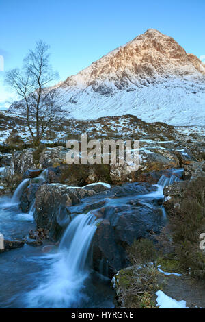 Blick auf den Wasserfall vor dem Schnee bedeckt Buachaille Etive Mor in Glencoe-Schottland Stockfoto