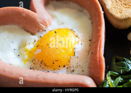 Spiegelei in der Pfanne in die Würstel Wurst Form des Herzens mit Mayonnaise und Gemüse Stockfoto