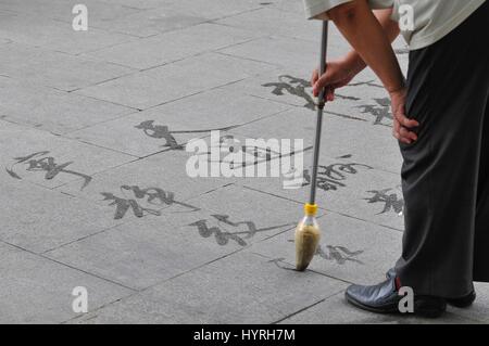 China, Beijing, Mann schreiben Kalligraphie auf dem Boden Stockfoto