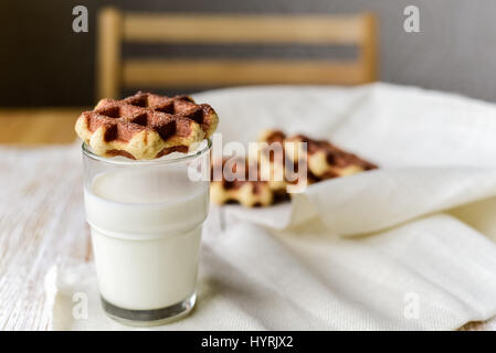 Hausgemachte belgische Lütticher Waffeln mit Glas Milch auf Tisch Stockfoto