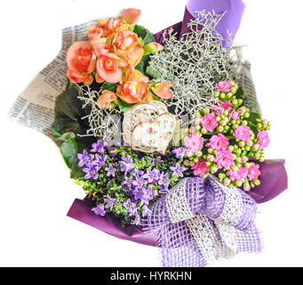 Blumenarrangement in Zeitungspapier mit wilden lila Blüten, rosa Calandiva Blumen, Kalanchoe, violette Bogen eingewickelt. Stockfoto