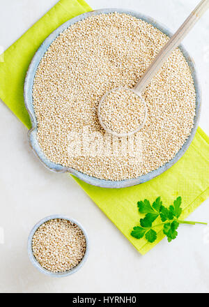 Vertikales Bild von Bio-Quinoa in eine große Keramikschale mit einem Löffel und einer kleinen Schüssel auf der linken Seite, Textfreiraum zur Verfügung. Stockfoto