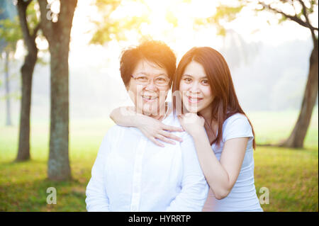 Porträt des asiatischen ältere Mutter und Tochter, ältere Erwachsene Frau und gewachsene Kind. Natur Familie im Naturpark mit schönen Sonne flare. Stockfoto