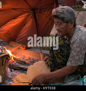 Quadratische Porträt einer armen Dame auf der Straße in Kambodscha süßer Reis Pfannkuchen zubereiten. Stockfoto