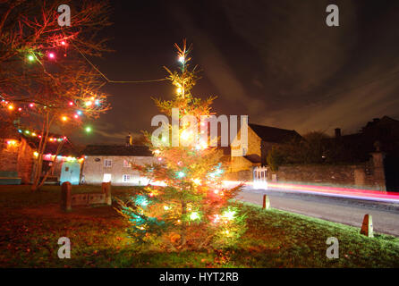 Weihnachtsschmuck durch die Holz- Bestände auf dem Dorfplatz im Eyam, Peak District National Park, England Großbritannien Stockfoto