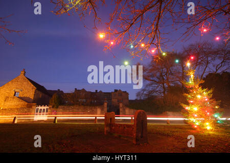 Weihnachtsschmuck durch die Holz- Bestände auf dem Dorfplatz im Eyam, Peak District National Park, England Großbritannien Stockfoto