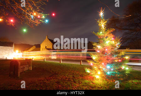 Weihnachtsschmuck durch die Holz- Bestände auf dem Dorfplatz im Eyam, Peak District National Park, England Großbritannien Stockfoto