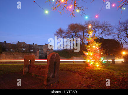 Weihnachtsschmuck durch die Holz- Bestände auf dem Dorfplatz im Eyam, Peak District National Park, England Großbritannien Stockfoto