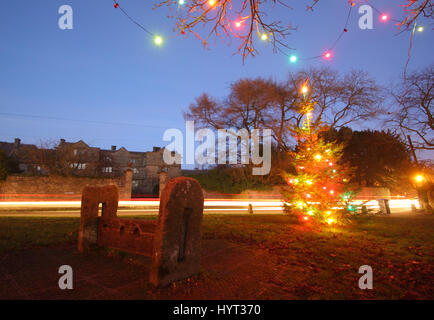 Weihnachtsschmuck durch die Holz- Bestände auf dem Dorfplatz im Eyam, Peak District National Park, England Großbritannien Stockfoto