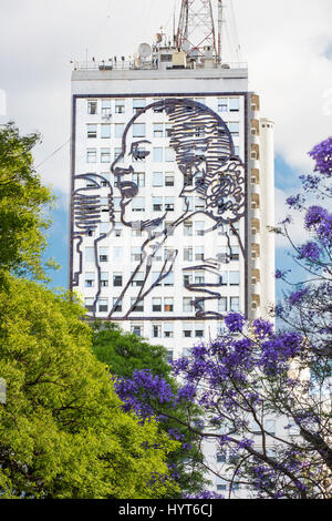 Die Installation von Evita auf dem Gebäude des Gesundheitsministeriums an der Avenida 9 de Julio im Frühling mit Jacaranda-Bäumen. Buenos Aires, Argentinien. Stockfoto
