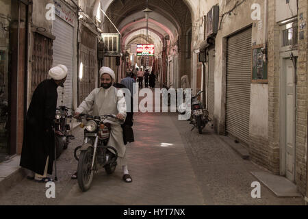 YAZD, IRAN - 18. August 2016: Iranische Imame Tracht diskutieren während auf einem Motorrad in einer überdachten Straße von Yazd Basar Überblick Stockfoto