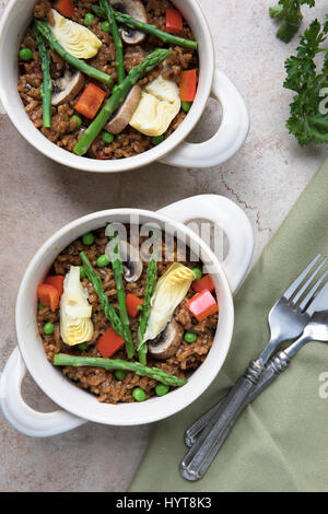 Zwei Schüsseln mit veganen Paella mit Spargel, Champignons und Artischockenherzen - lag flach. Stockfoto