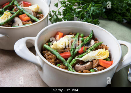 Gesunde Schale mit veganen Paella mit Spargel, Champignons und Artischockenherzen. Stockfoto