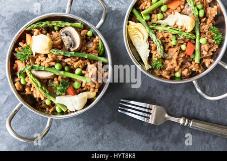 Zwei Schüsseln mit veganen Paella mit Spargel, Champignons und Artischockenherzen - lag flach. Stockfoto