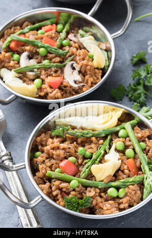 Zwei Schüsseln mit veganen Paella mit Spargel, Champignons und Artischockenherzen. Stockfoto