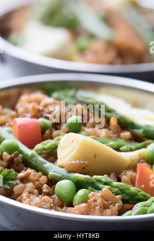 Gesunde Schale mit veganen Paella mit Spargel, Champignons und Artischockenherzen. Stockfoto